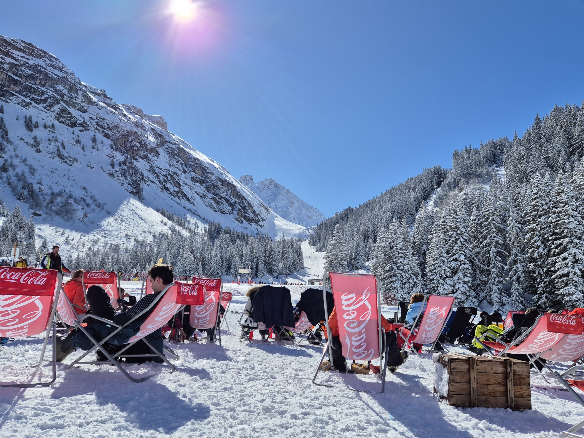 Snow and deckchairs at one of the best Three Valleys snack bars, in Courchevel, with mountains and forest behind