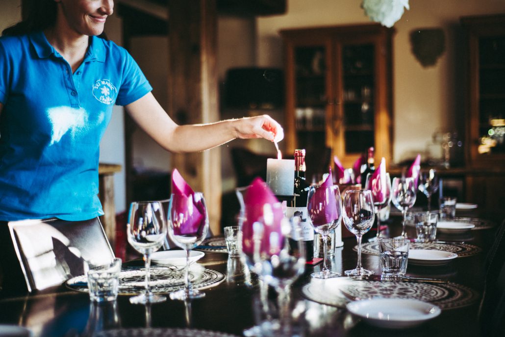 Booking a last minute ski holiday: Dos and Don’ts! 3 Ski Magic chalet host lights a candle on a table laid for chalet dinner