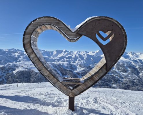 Meribel heart sculpture seat with snowy mountains in the background