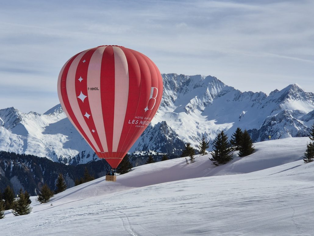 Booking a last minute ski holiday: Dos and Don’ts! 2 A red and white striped hot air balloon touches down on the snowy ski slope in Courchevel