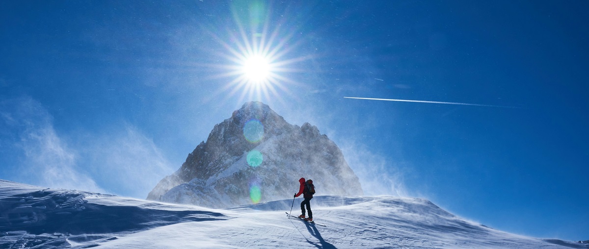 Ein Mann beim Skitourengehen in einer verschneiten Winterlandschaft. Entdecken Sie Skitouren in La Tania