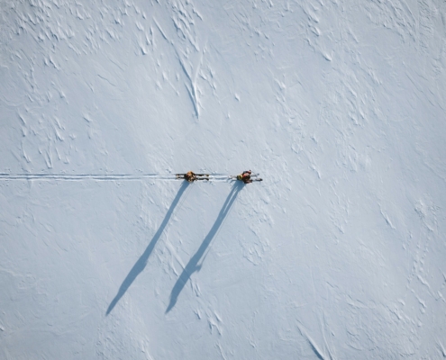 Two people ski touring against a snowy backdrop