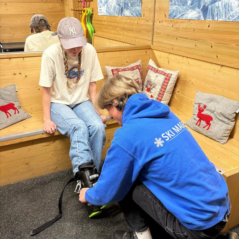 Ski technician fitting hire ski boots for a guest in a La Tania chalet